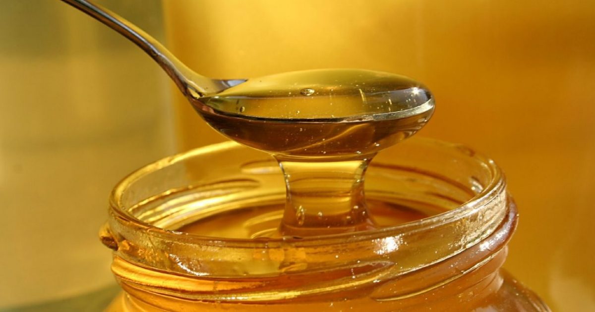 honey on a spoon over jar